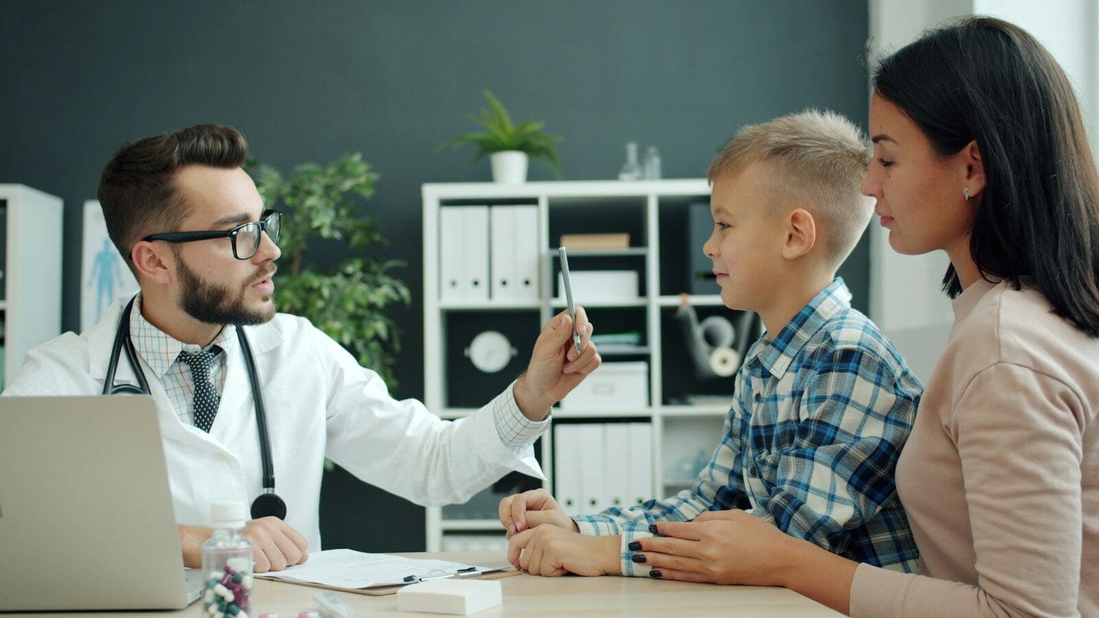 Doctor examines a young boy with his mother present